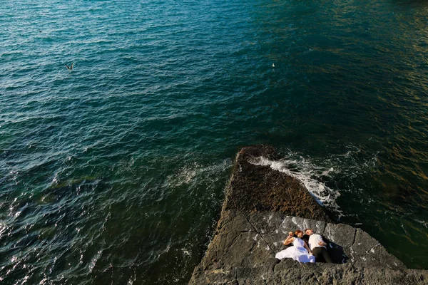 Sposo e sposa sulle rocce in riva al mare — Foto Stock