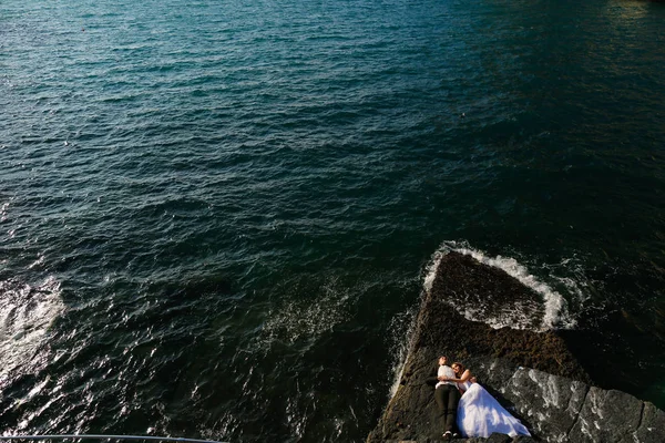 Brudgummen och bruden på klipporna vid havet — Stockfoto