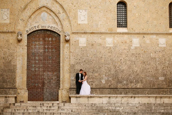 Noiva e noivo perto da porta da igreja — Fotografia de Stock