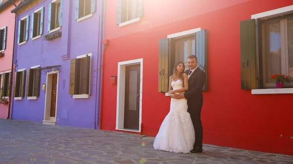 Novio y novia posando frente a una casa roja — Foto de Stock
