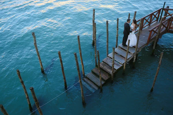 Novio y novia en una cubierta cerca del agua —  Fotos de Stock