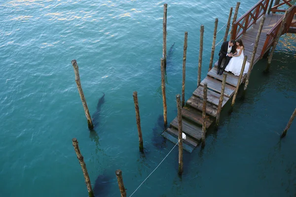 Sposo e sposa su un ponte vicino all'acqua — Foto Stock