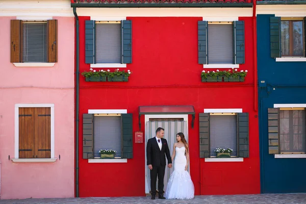 Novio y novia posando frente a una casa roja —  Fotos de Stock