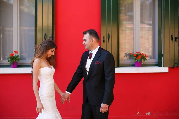 Brudgummen och bruden poserar framför ett rött hus — Stockfoto