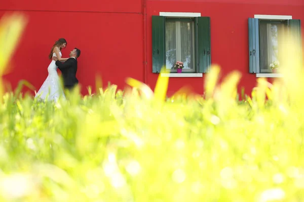 Damat ve gelin kırmızı bir evin önünde poz — Stok fotoğraf