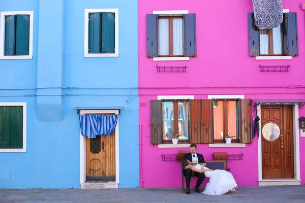 Sposo e sposa di fronte a una casa blu e viola — Foto Stock