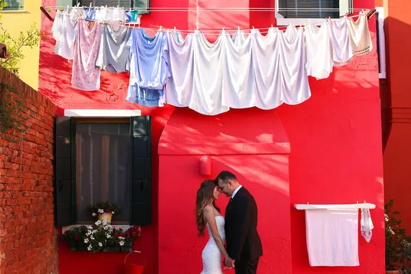 Novio y novia posando frente a una casa roja —  Fotos de Stock