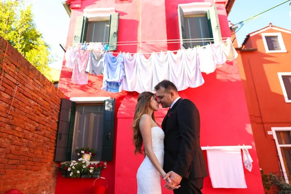 Groom and bride posing in front of a red house — Stock Photo, Image