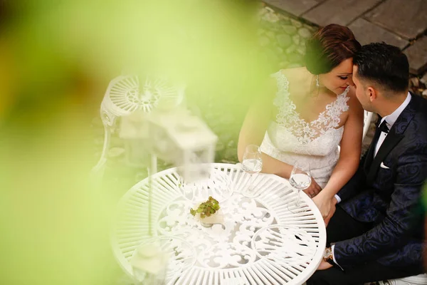 Bride and groom kissing at a table — Stock Photo, Image