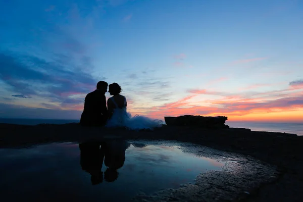 Silhouette eines Bräutigams und einer Braut, die sich in der Abenddämmerung küssen — Stockfoto