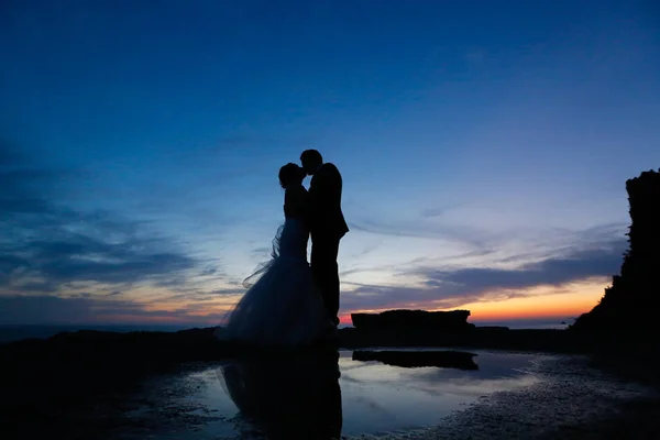 Silhouette di uno sposo e una sposa che si baciano al tramonto — Foto Stock