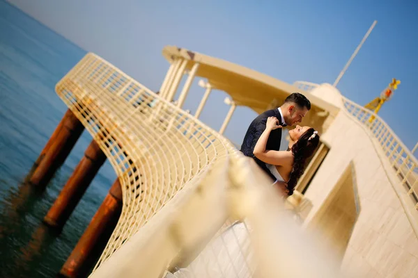 Novio y novia besándose en un puente cerca del mar —  Fotos de Stock