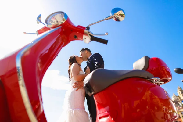 Vőlegény és menyasszony piros robogó közelében csók — Stock Fotó