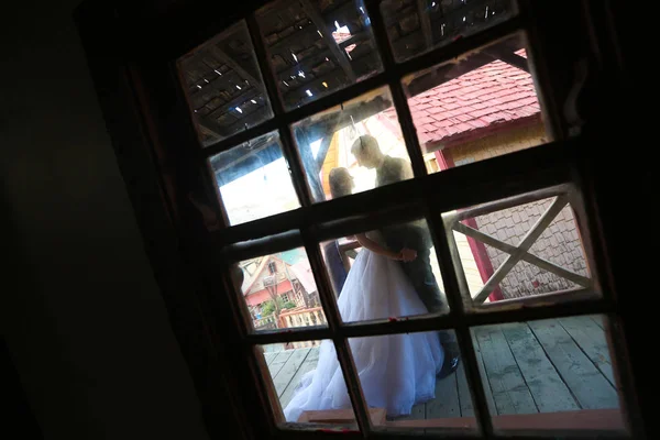 Groom and bride seen trough a window — Stock Photo, Image