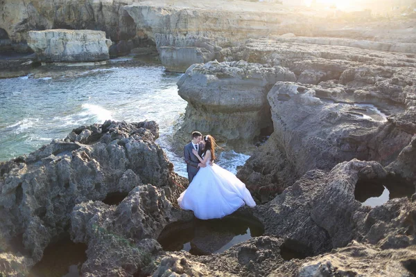 Brudgummen och bruden på klipporna nära havet — Stockfoto