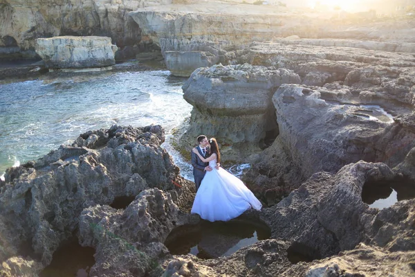 Γαμπρός και νύφη στα βράχια κοντά στην θάλασσα — Φωτογραφία Αρχείου