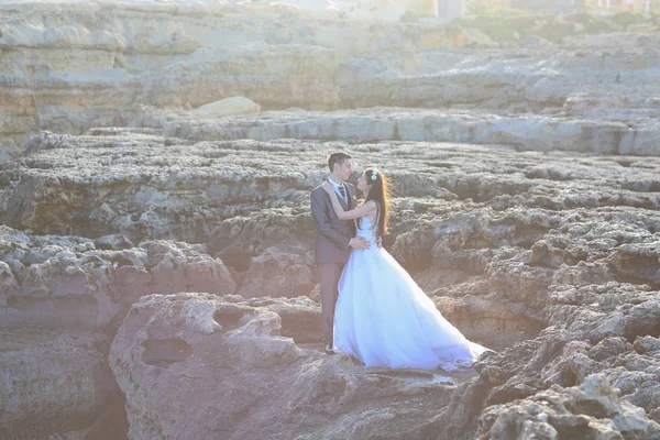 Novio y novia en las rocas cerca del mar —  Fotos de Stock