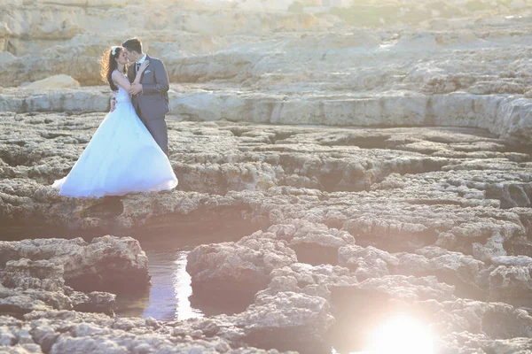 Brudgummen och bruden på klipporna nära havet — Stockfoto