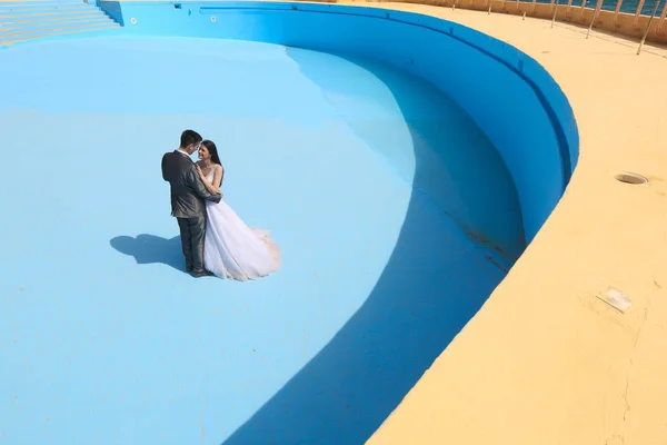 Groom and bride in a empty pool — Stock Photo, Image