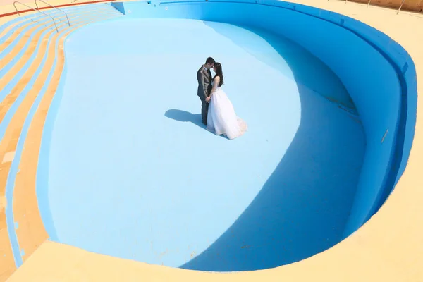 Sposo e sposa in una piscina vuota — Foto Stock