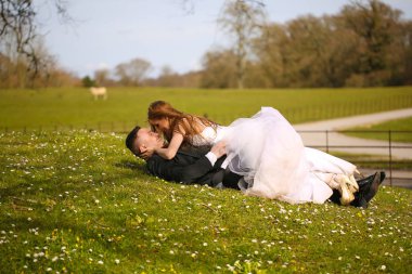 Damat ve gelin çim ve öpüşme, seçici odak üzerinde döşeme