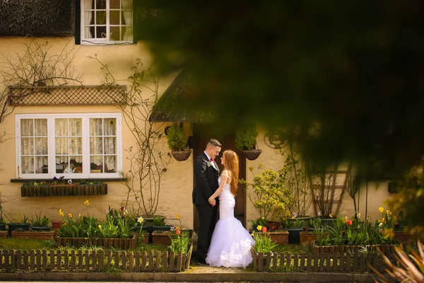 Novio y novia posando frente a una casa — Foto de Stock