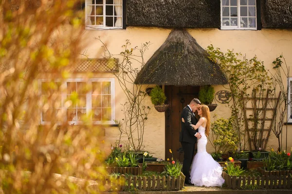 Groom and bride posing in front of a house — Stock Photo, Image