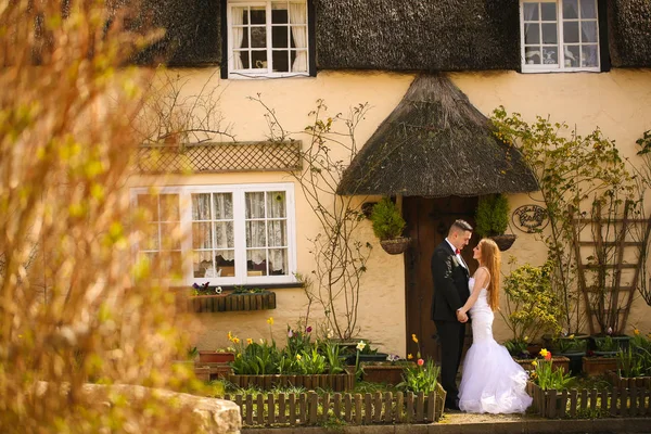 Groom and bride posing in front of a house — Stock Photo, Image