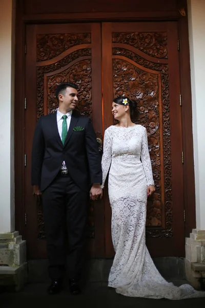 Свадебная пара позирует против деревянной двери — стоковое фото