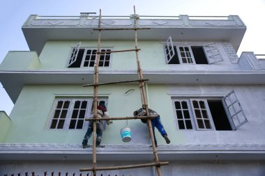 Kathmandu, Nepal - 7 Şubat 2020: Boya Fırçası ve Boya Kovası ile evin dış kısmını Bambu Merdiveni 'nin yardımıyla boyayan Boyacılar