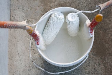 Kovanın içinde boya fırçaları ve silindirli boya kovası.