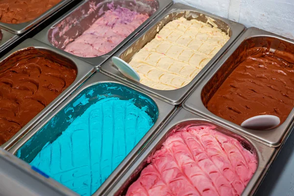 Farklı aromalı dondurma tezgahında bir sürü kepçe aromalı dondurma. Tezgahta çeşitli Icecream tatları var.