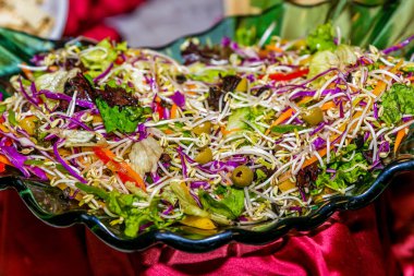 Masada yeşil sebze salatası var. Yemek servisi masasında.