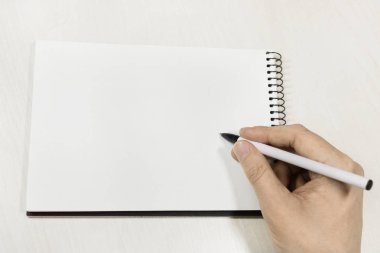 Beyaz ahşap masa üzerinde beyaz eskiz defteri üzerinde el