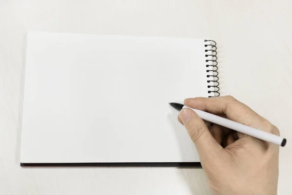 Beyaz ahşap masa üzerinde beyaz eskiz defteri üzerinde el