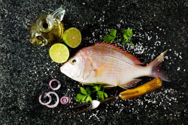 taze balık ve malzemeler: limon, maydanoz, zeytinyağı, mavi soğan