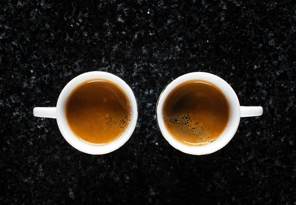 Dos tazas de café expreso fresco en mármol negro — Foto de Stock