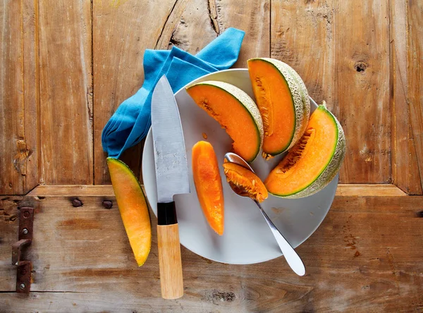 Cut Melon on a wooden table and a knife — Stock Photo, Image