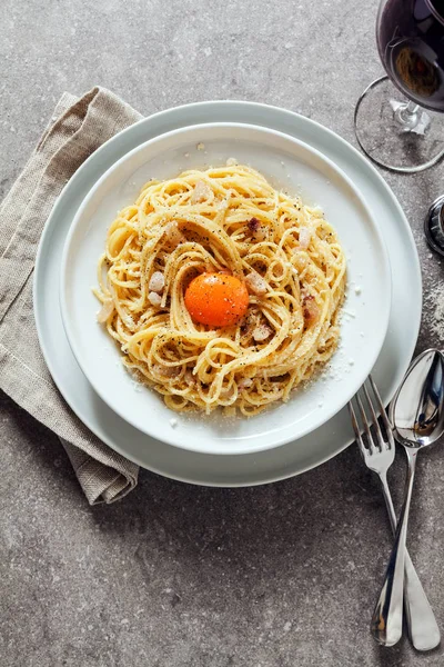Pasta Carbonara on white plate with parmesan, red wine and yolk — Stock Photo, Image