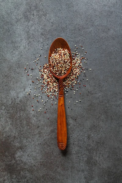 Quinoa dans une cuillère en bois sur un fond sombre — Photo