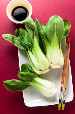 fresh not cooked bok choy and soy sauce on Cerise background. Ch clipart