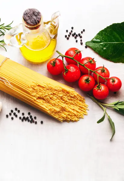 Spagetti makarna üzerine beyaz bir backgrou yemek pişirmek için malzemelerle