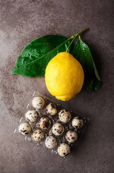 Verse grote citroen met bladeren en kwartel eieren op een grijze pagina — Stockfoto