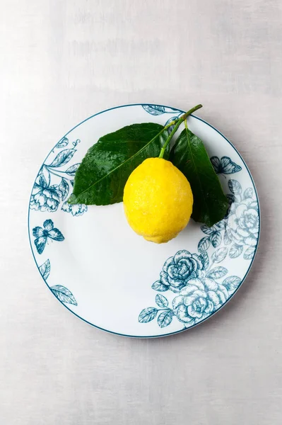Frische große natürliche Zitrone mit Blättern auf einem Teller — Stockfoto
