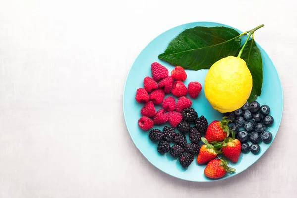 Mixed fresh ripe berries on blue plate on white background — Stock Photo, Image