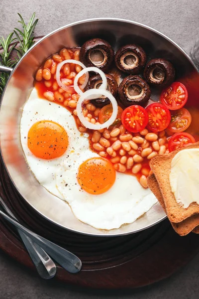 Café da manhã com ovos fritos em panela de ferro fundido, ovo quebrado, tomates — Fotografia de Stock