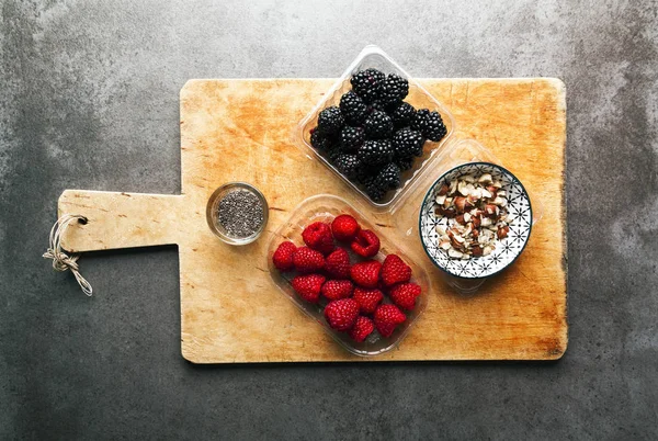 Fresh forest berries on a cutting board with crushed nuts. On a — Stock Photo, Image