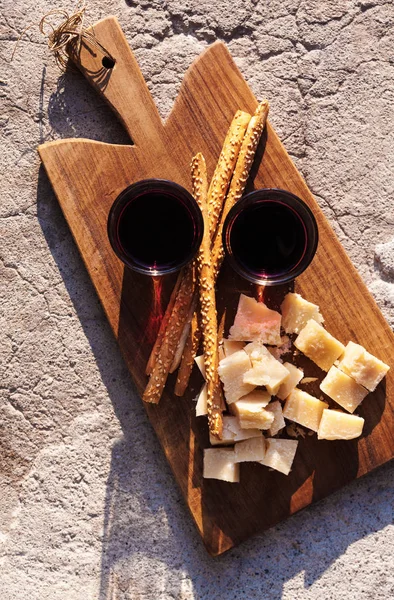 Vinho e queijo parmesão em uma tábua de corte na luz quente de — Fotografia de Stock