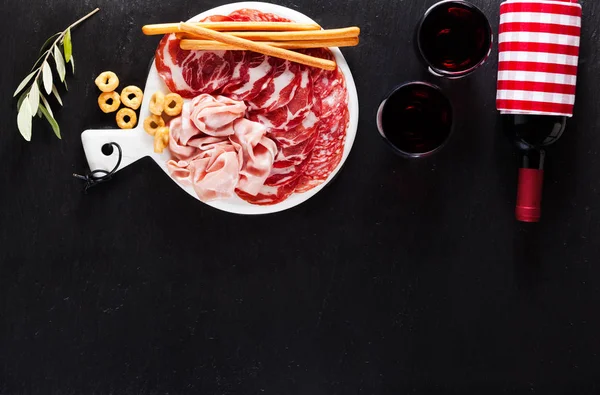 Carne fria cortada de diferentes variedades de salame em um backg escuro — Fotografia de Stock