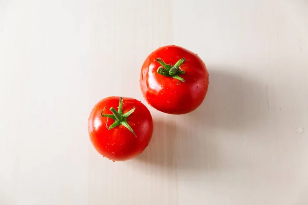 Dois tomates maduros vermelhos em uma mesa de cozinha de madeira clara — Fotografia de Stock